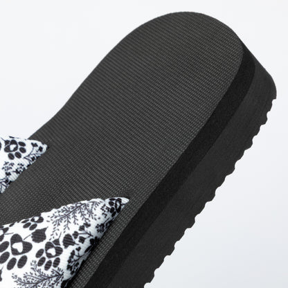 Black sandal with floral pattern on a light gray background