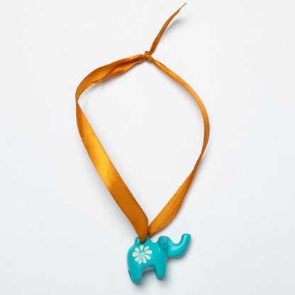 Ornament with a turquoise elephant pendant on an orange ribbon against a white background