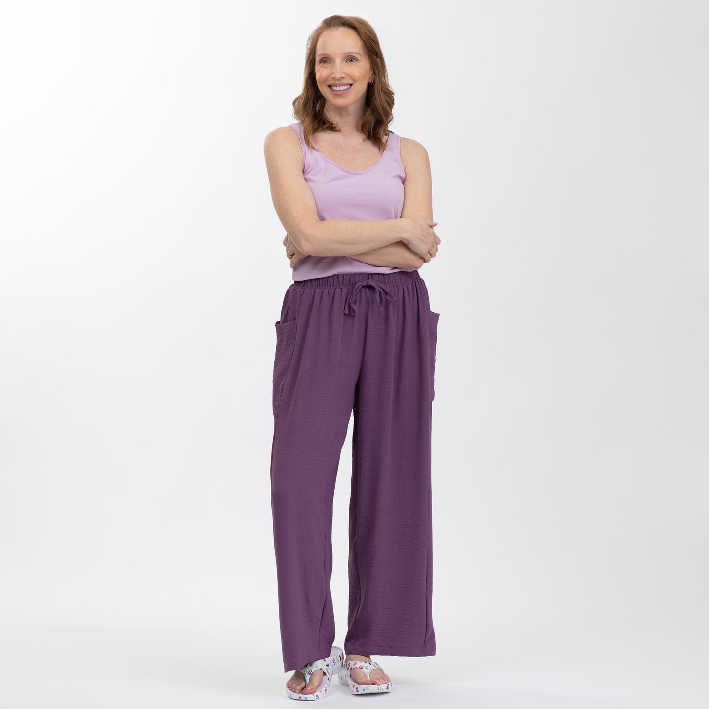 Woman wearing a purple tank top and pants on a white background