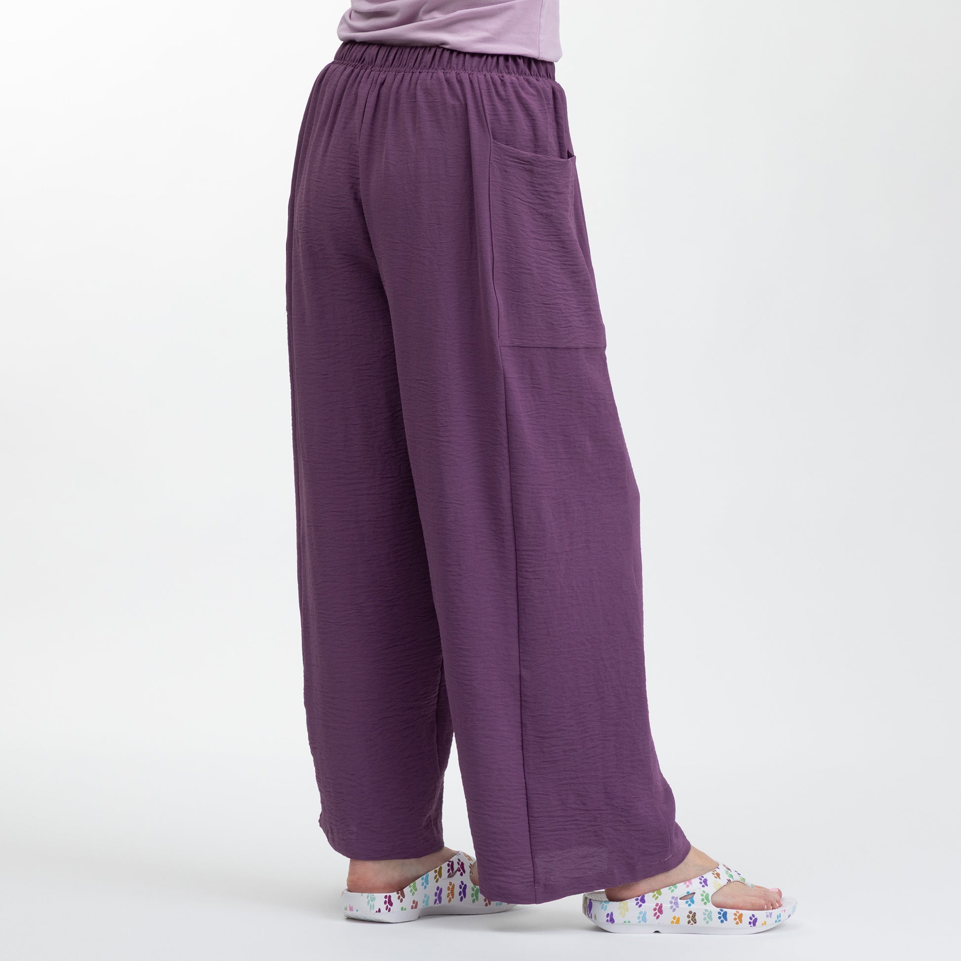 Purple wide-leg pants worn by a person on a white background