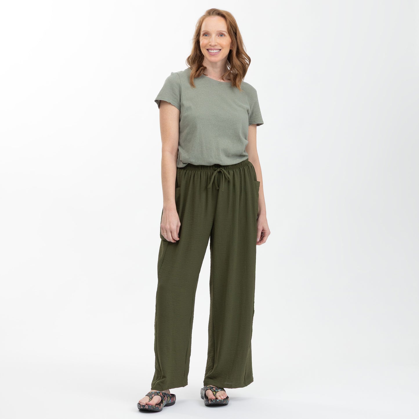 Woman wearing a green top and matching pants on a white background