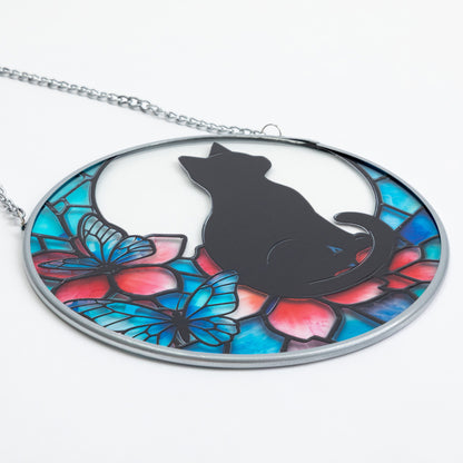 Close up of stained glass style sun catcher featuring a cat silhouette and flowers and butterflies in teal and pink.