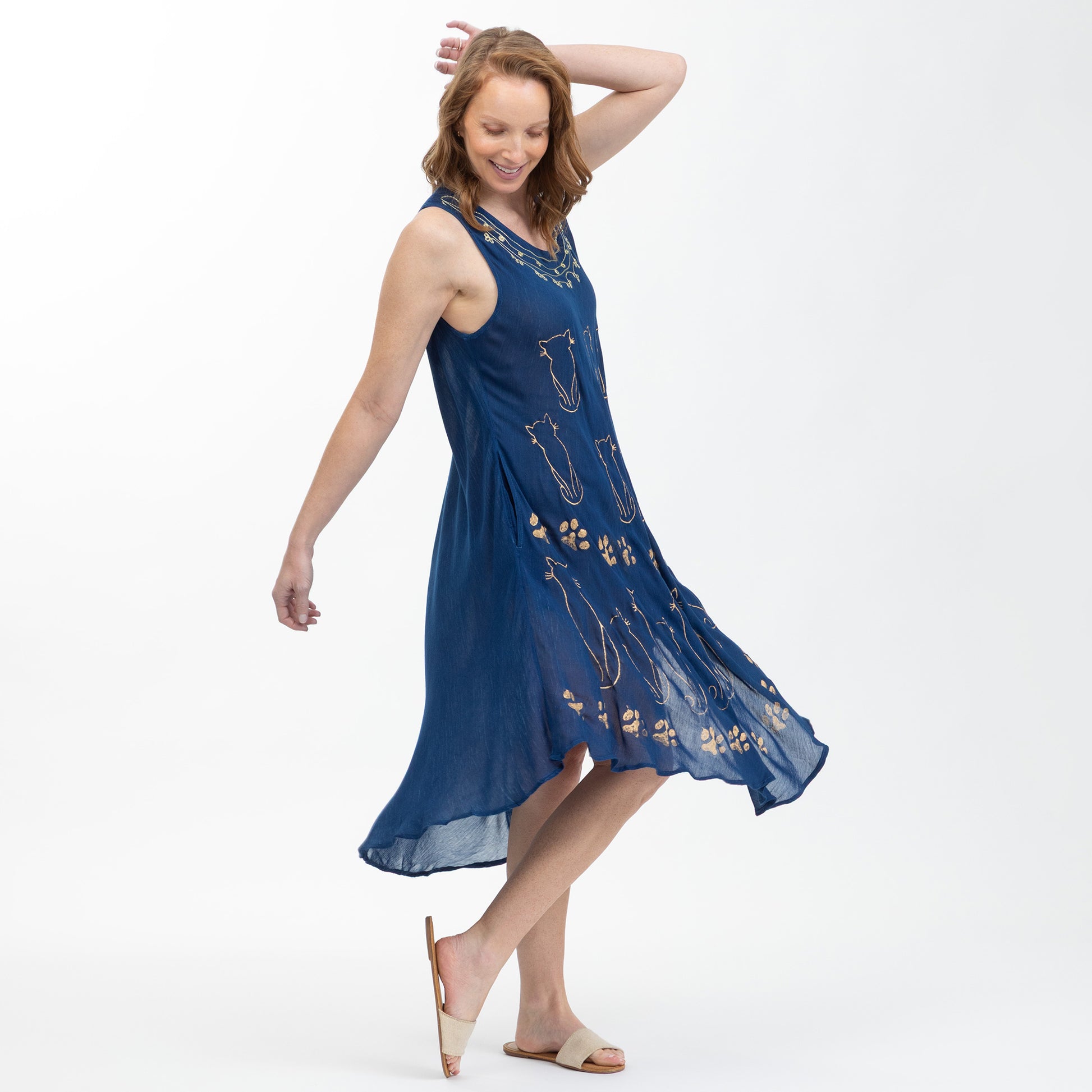 Woman wearing a blue dress with paw print and cat patterns on a white background