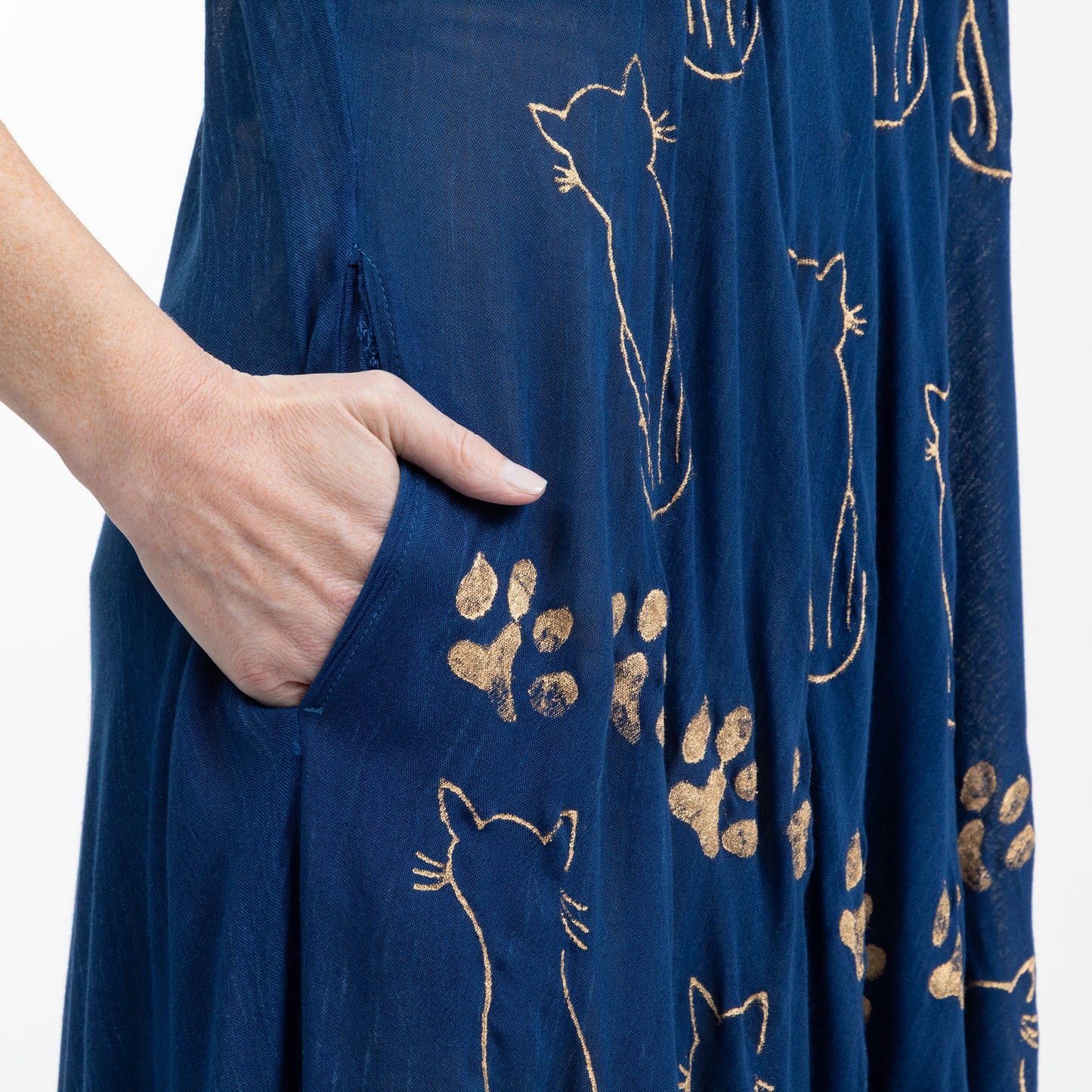 Navy blue fabric on a dress with gold cat and paw print patterns, with a hand in the side pocket