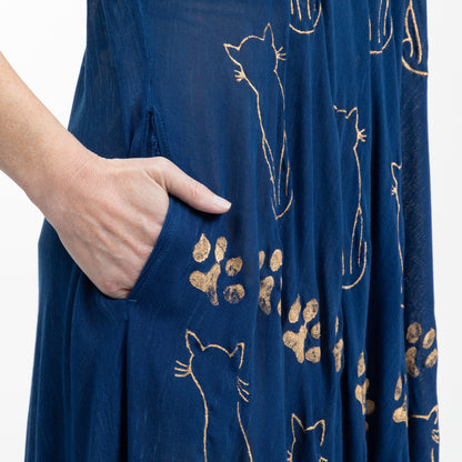 Navy blue fabric on a dress with gold cat and paw print patterns, with a hand in the side pocket