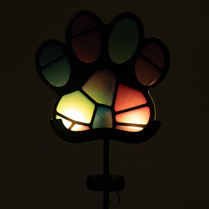 Colorful paw-shaped glowing garden stake on a black background