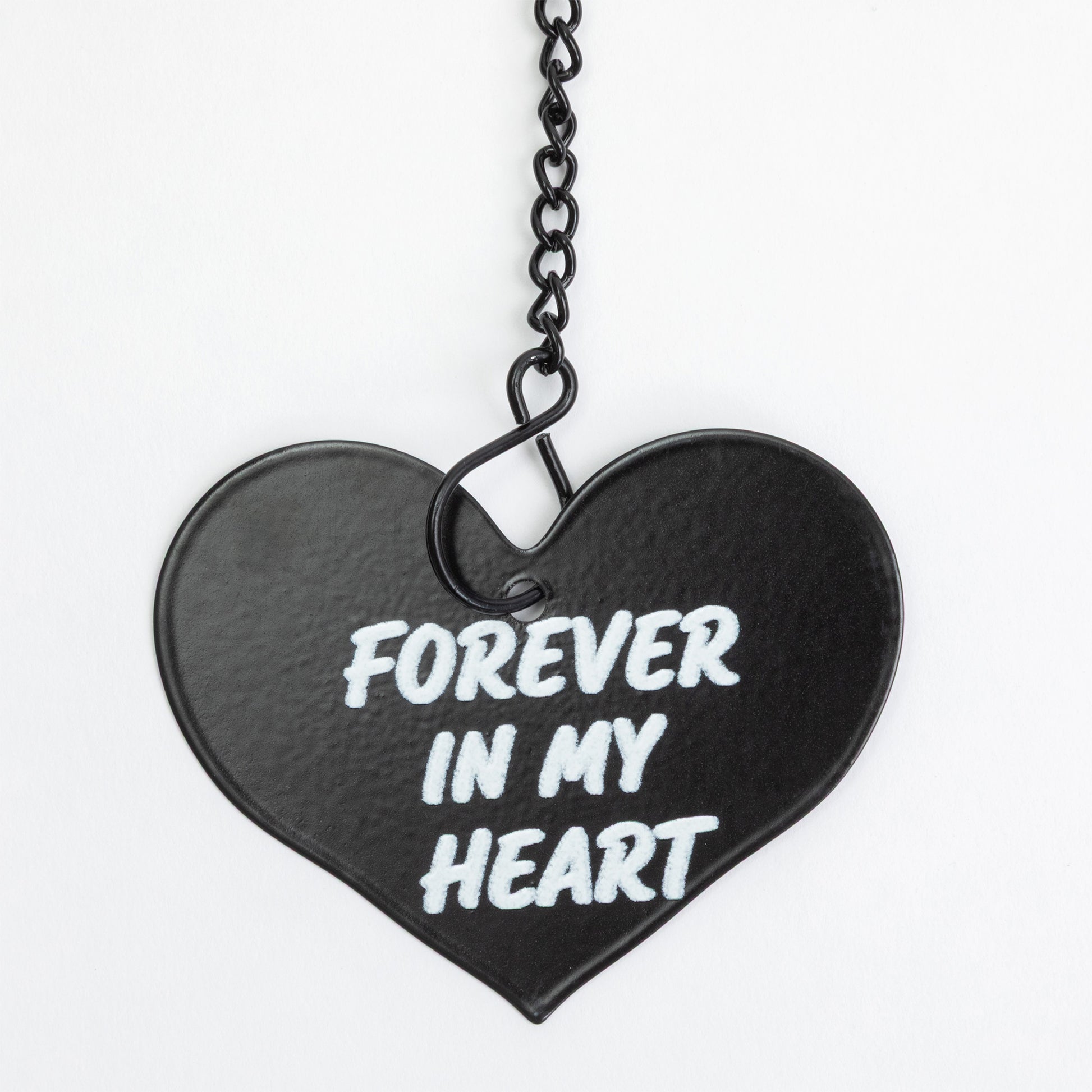 A black heart-shaped pendant with the words 'FOREVER IN MY HEART' in white lettering, suspended from a black chain against a plain white background.