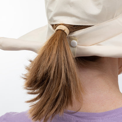 Person with a ponytail wearing a beige sun hat on a white background
