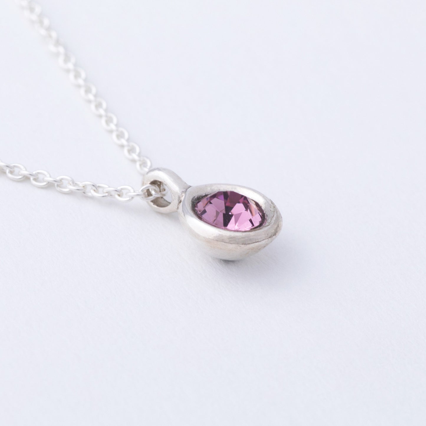 Necklace with a teardrop-shaped pink gemstone on a white background