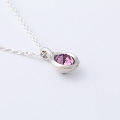 Necklace with a teardrop-shaped pink gemstone on a white background