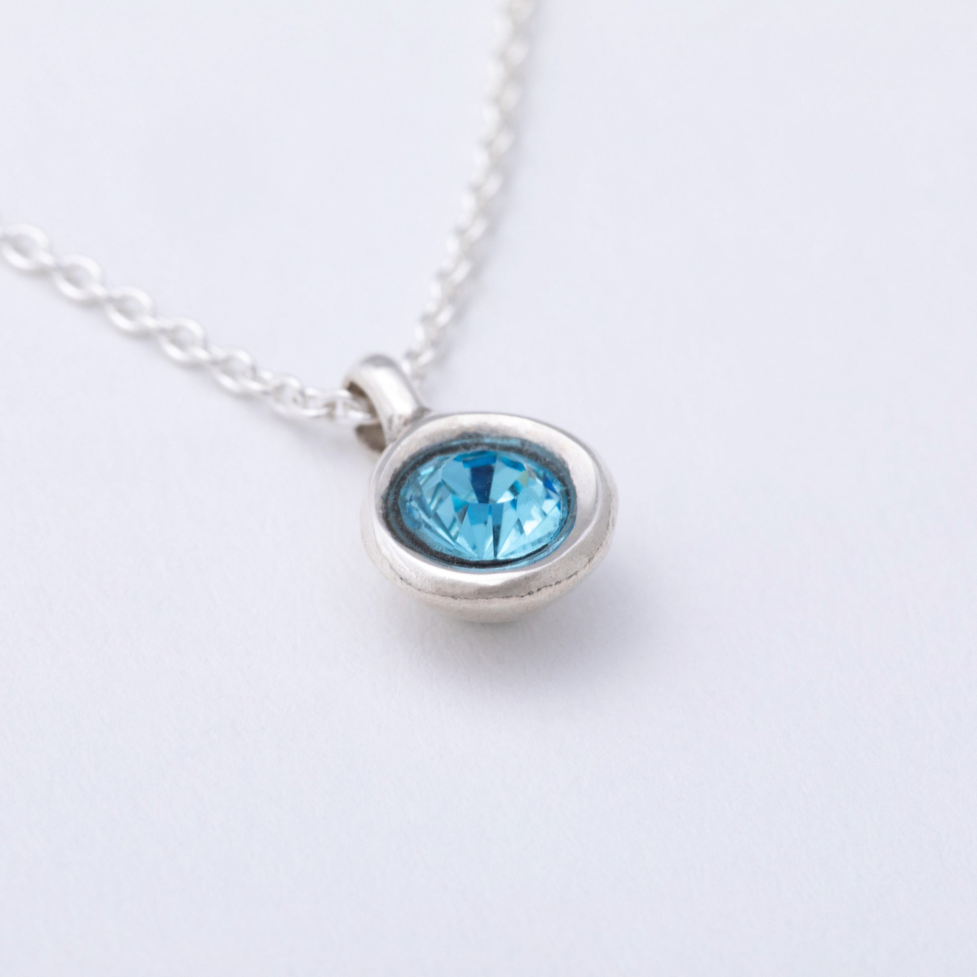 Silver necklace with a blue gemstone on a white background