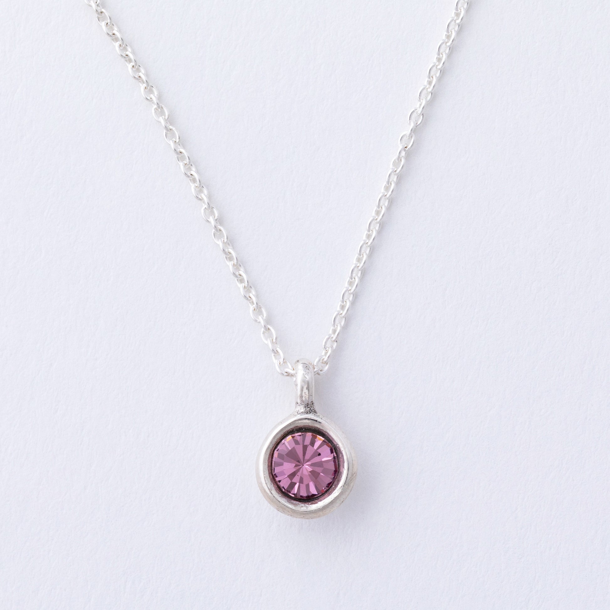 Silver necklace with a pink gemstone pendant on a light gray background