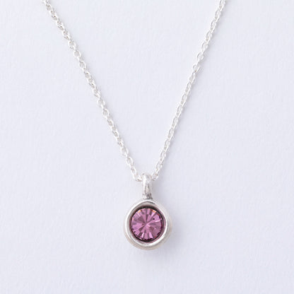Silver necklace with a pink gemstone pendant on a light gray background