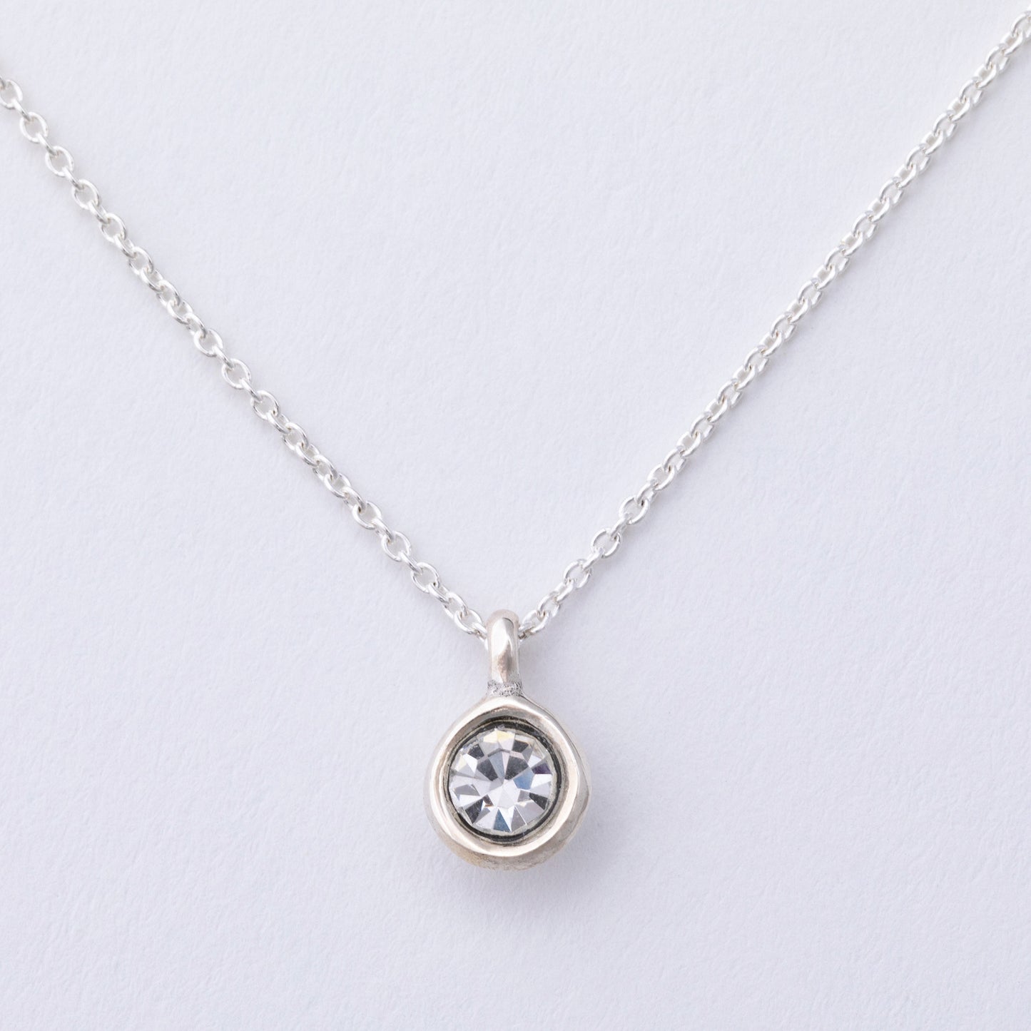Silver necklace with a round pendant on a light gray background