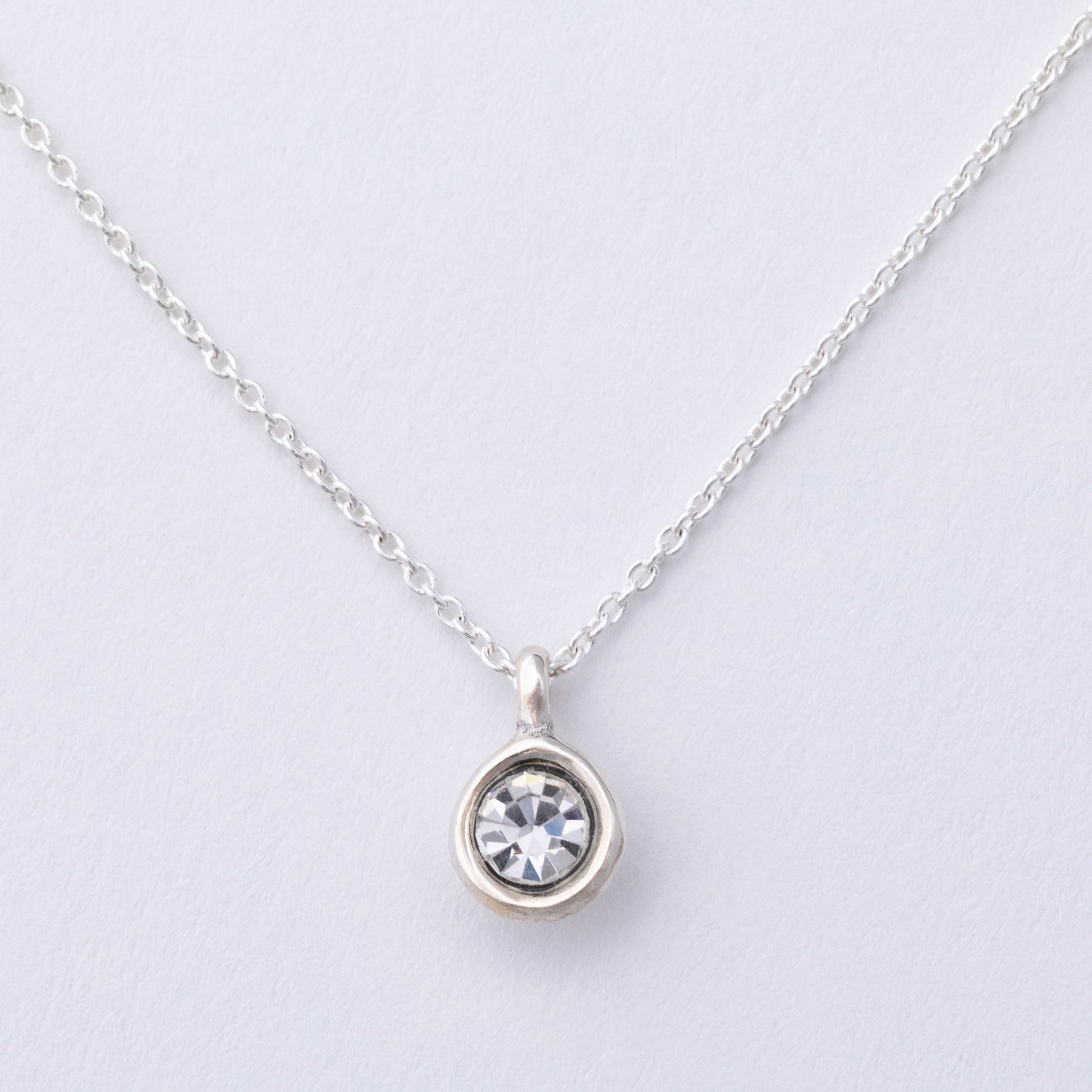 Silver necklace with a round pendant on a light gray background