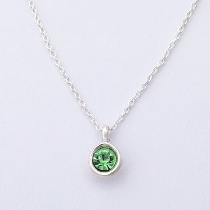 Silver necklace with a green gemstone pendant on a light gray background