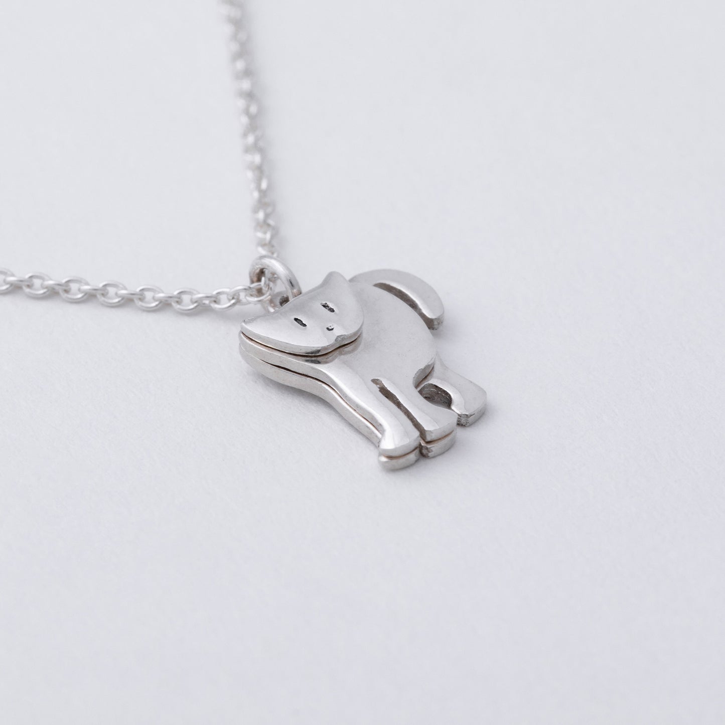 Silver horse-shaped pendant on a chain against a light gray background