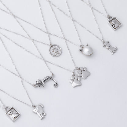 Collection of silver necklaces with various pendants on a light gray background