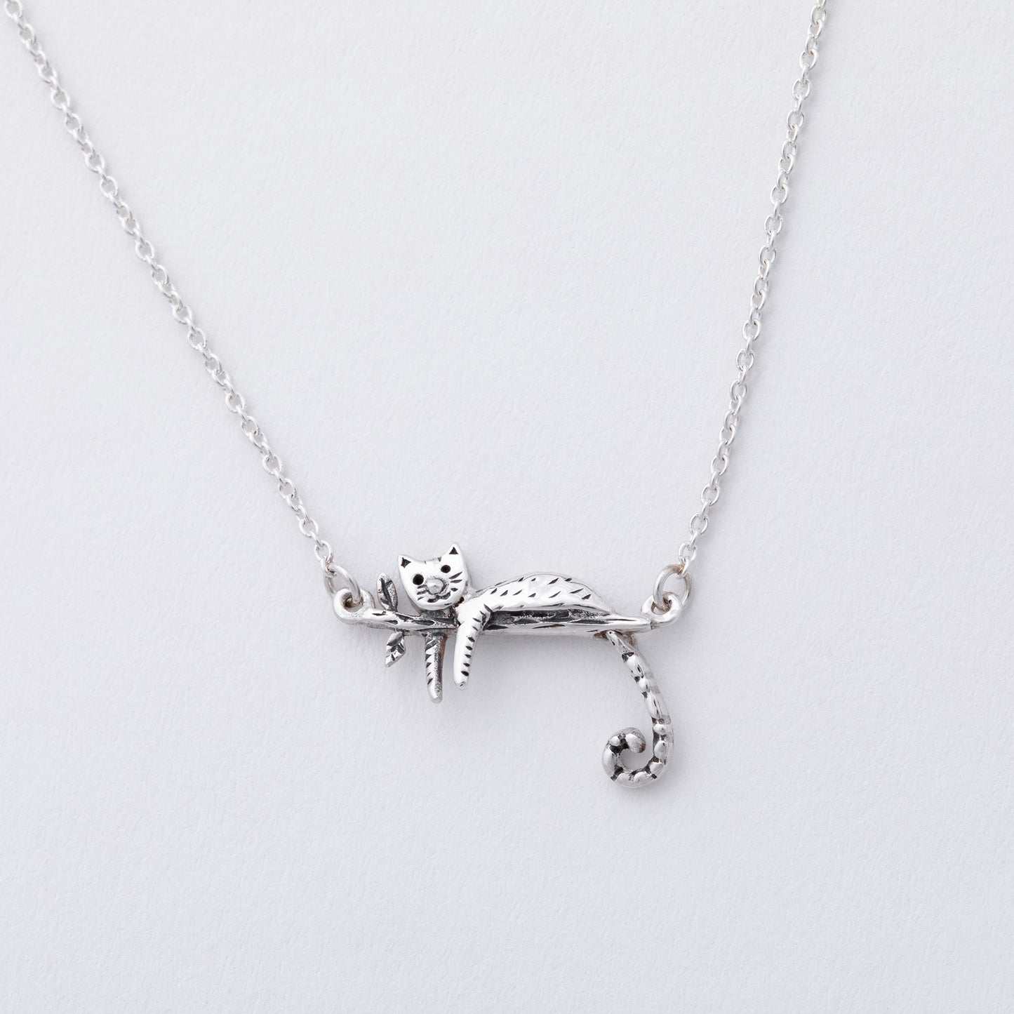 Silver cat-shaped pendant on a chain against a light gray background