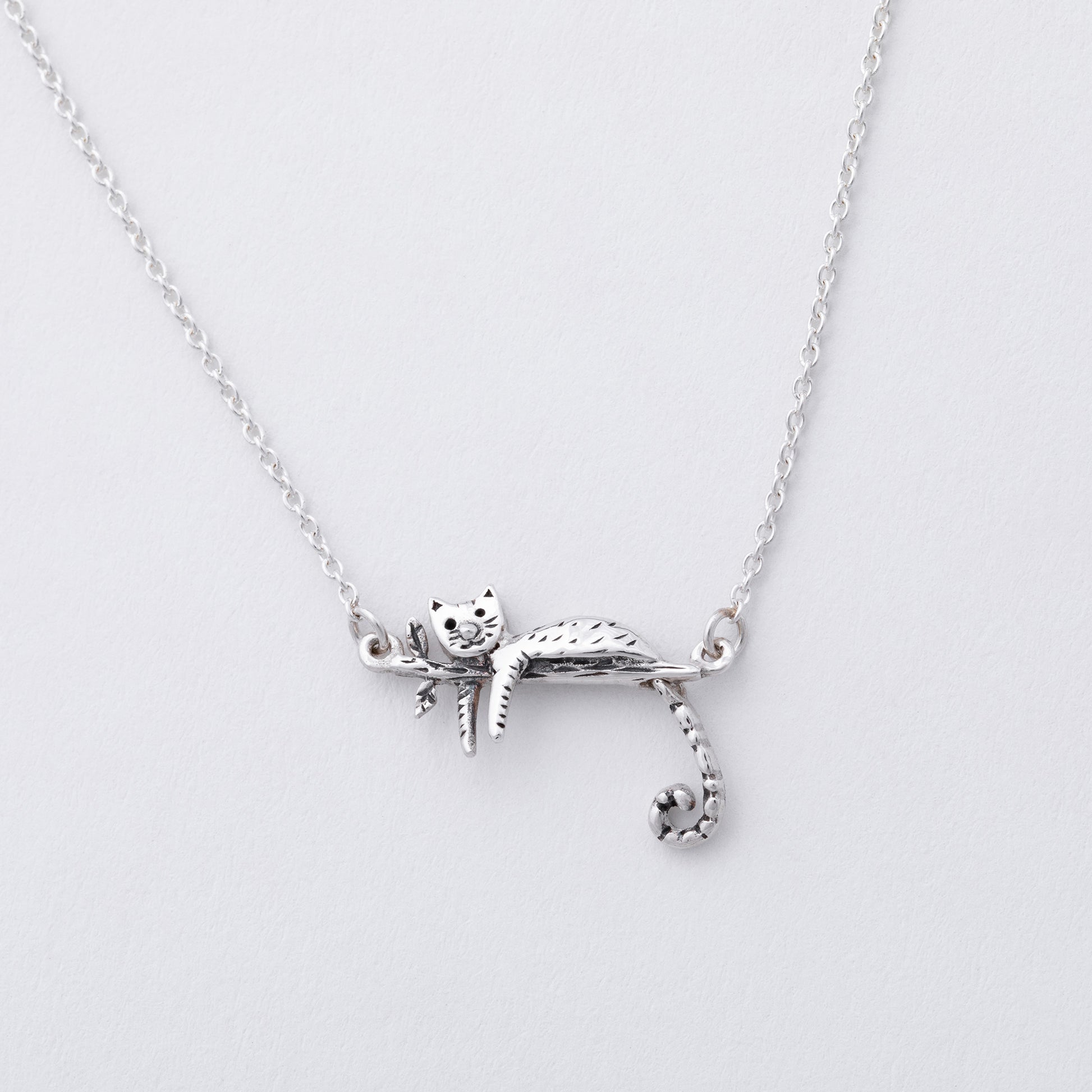 Silver cat-shaped pendant on a chain against a light gray background