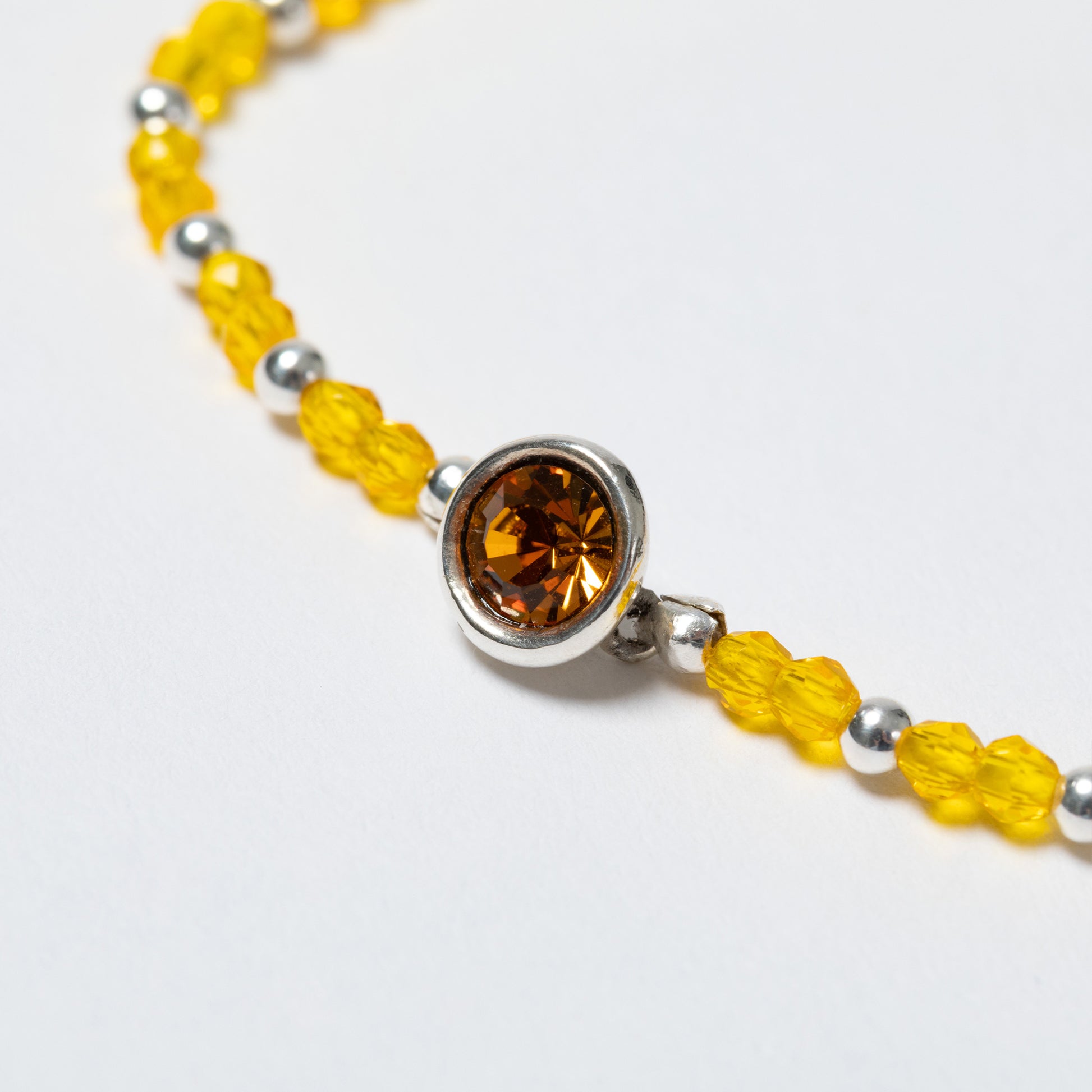 Bracelet with yellow beads and a brown gemstone on a white background