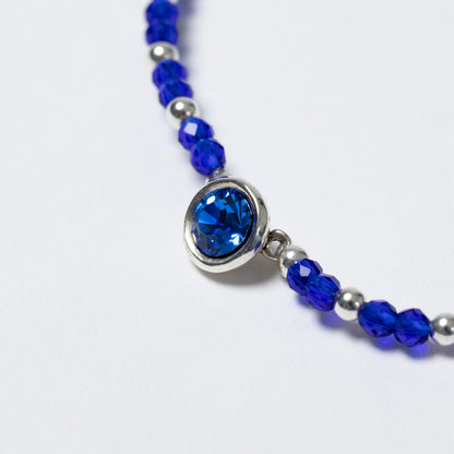 Bracelet with blue beads and a silver clasp on a white background