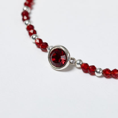 Bracelet with red beads and a silver clasp on a white background