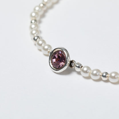 Pearl bracelet with a pink gemstone on a white background