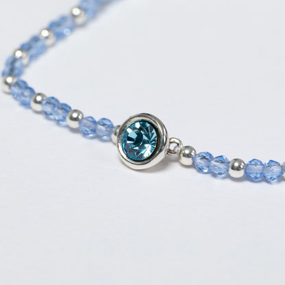 Necklace with blue and silver beads on a light gray background