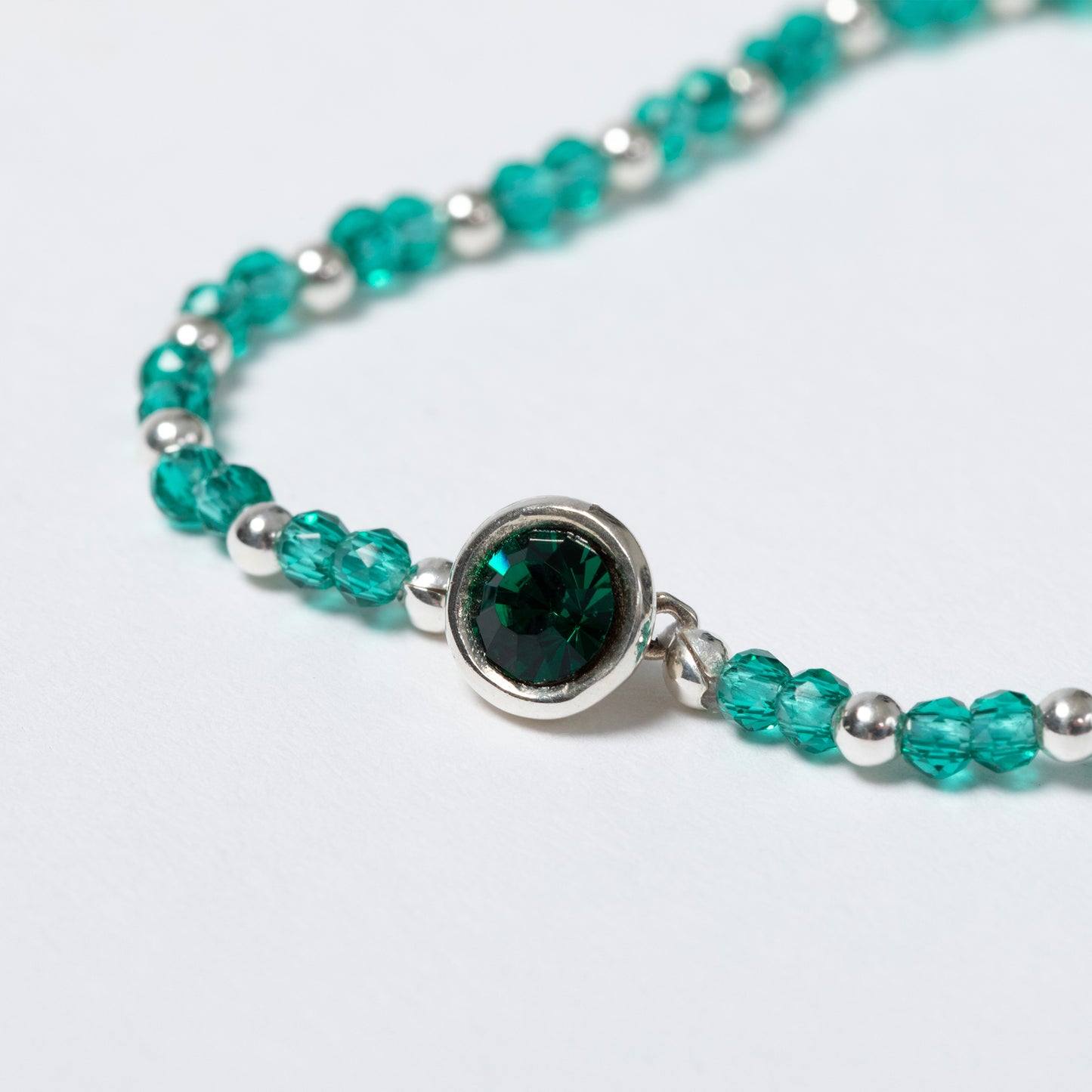 Bracelet with green gemstone and silver beads on a light gray background
