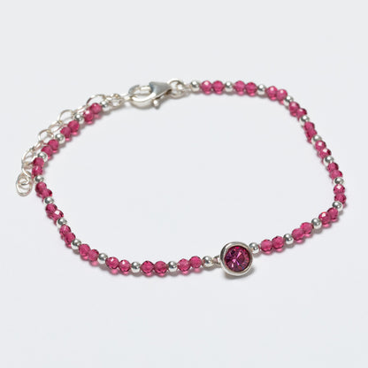 Bracelet with pink beads and a silver clasp on a light gray background