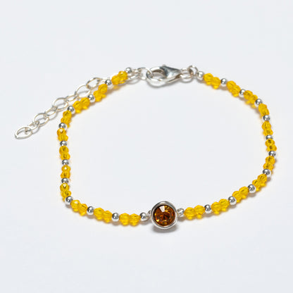 Yellow beaded bracelet with a silver clasp on a white background