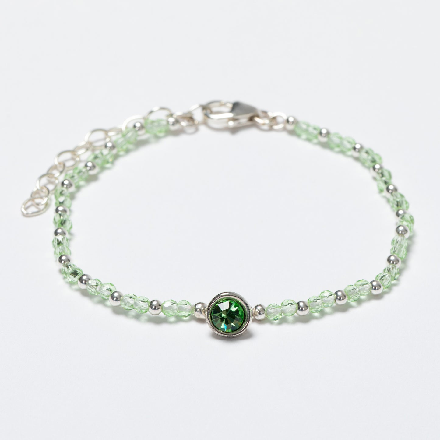 Silver bracelet with a green gemstone on a white background