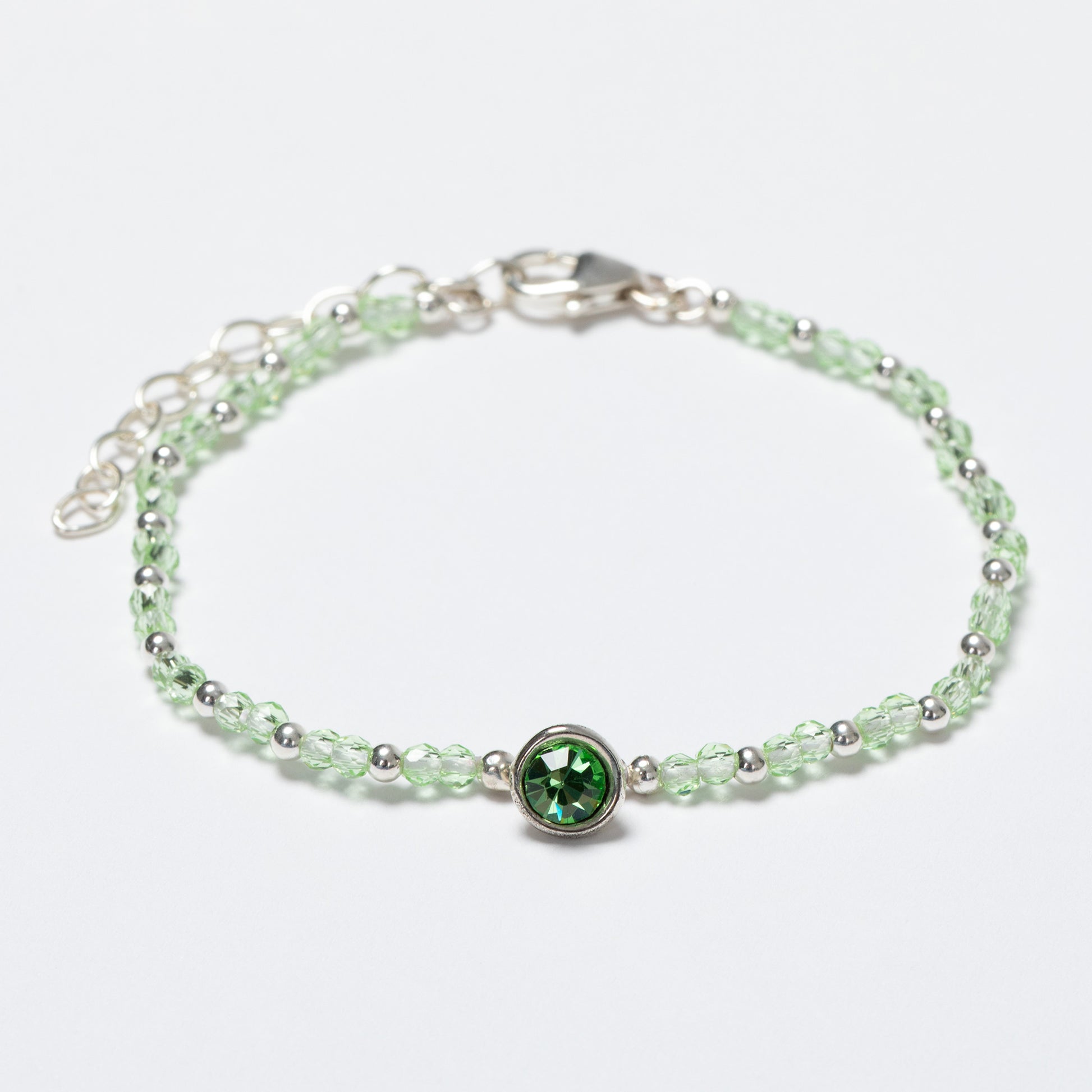 Silver bracelet with a green gemstone on a white background