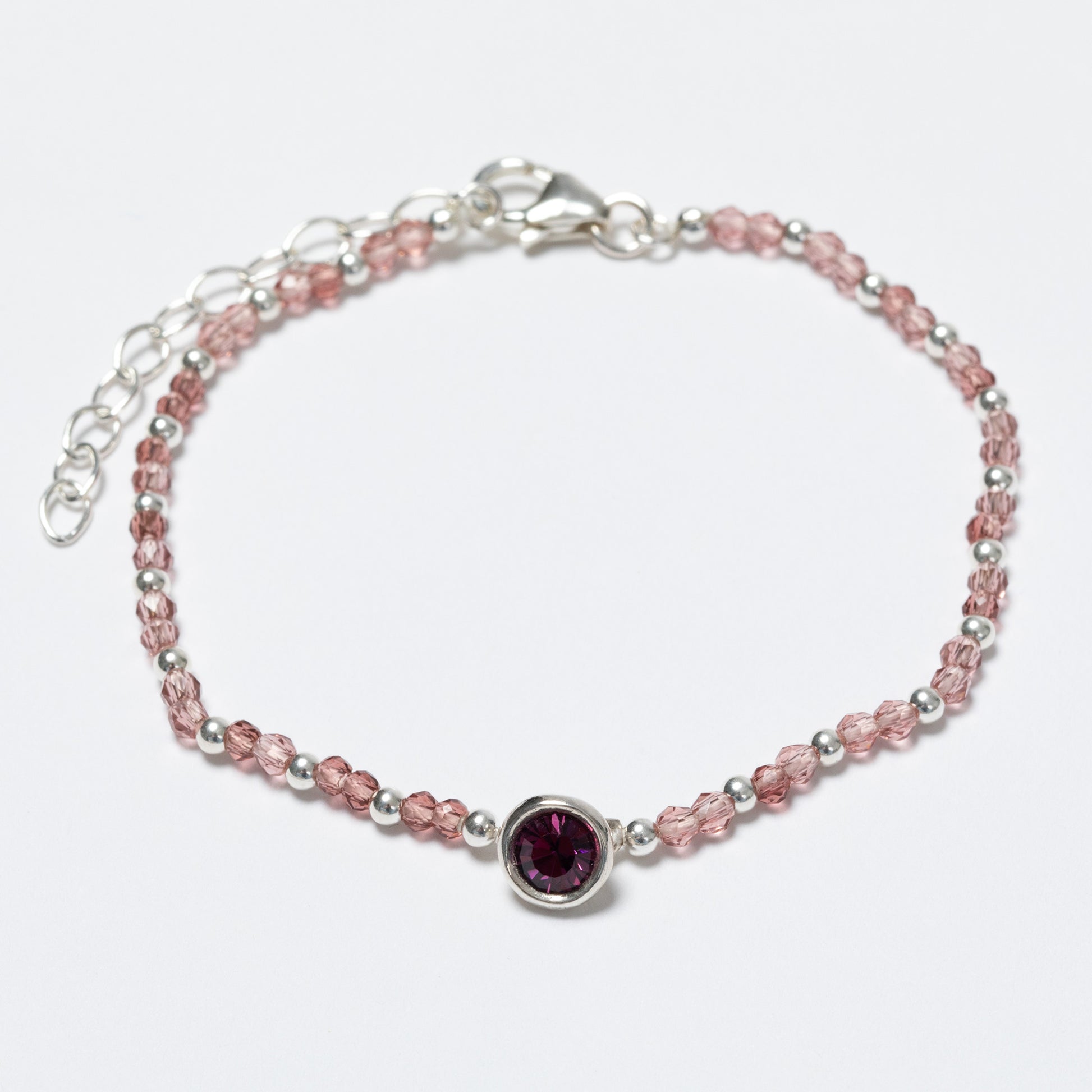 Bracelet with pink beads and a purple gemstone on a white background
