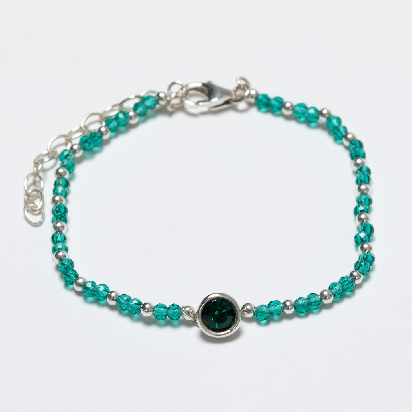 Beaded bracelet with green and silver beads on a white background