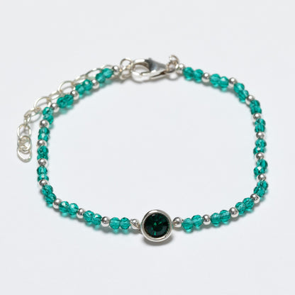 Beaded bracelet with green and silver beads on a white background