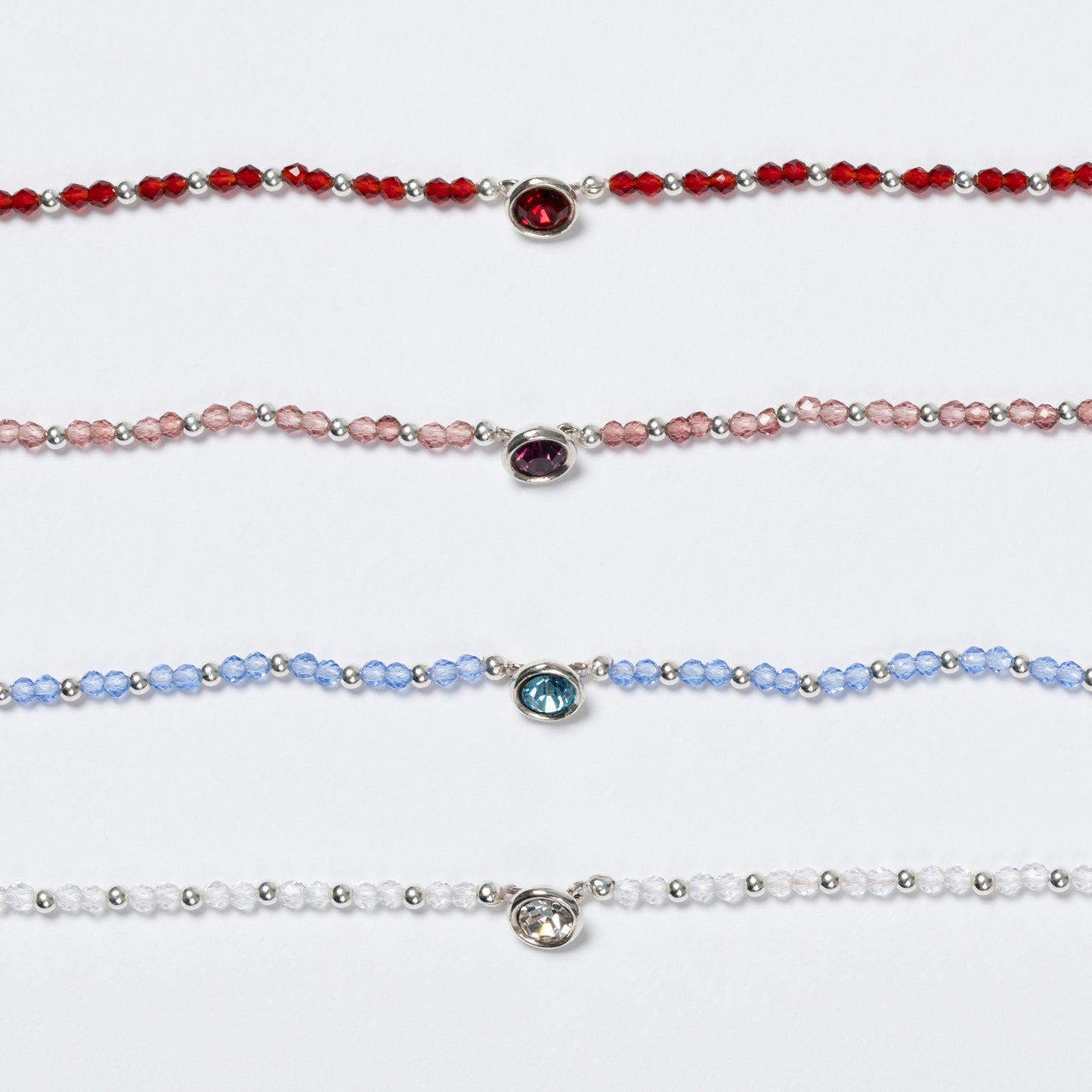 Four beaded bracelets with colored gemstones on a white background