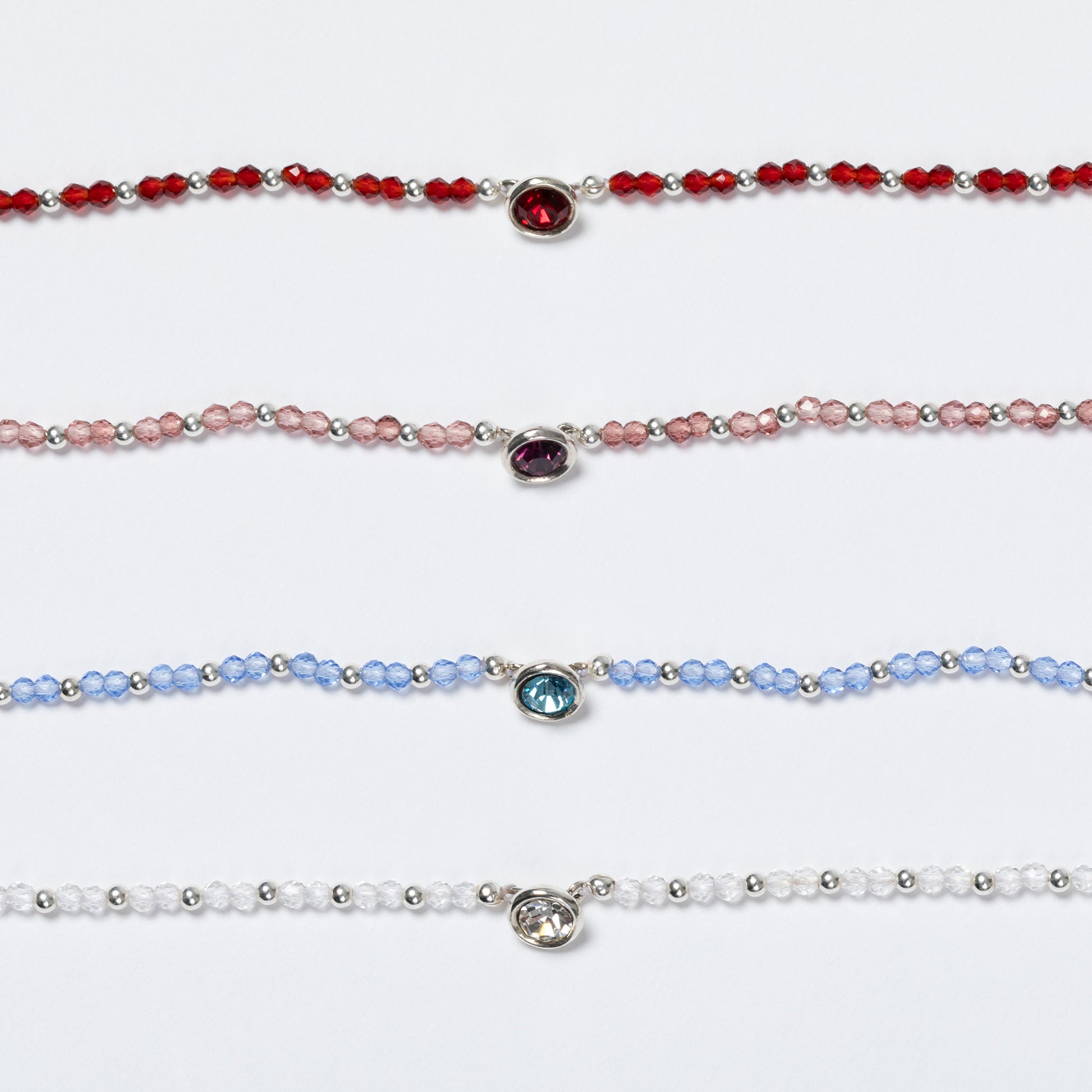 Four beaded bracelets with colored gemstones on a white background