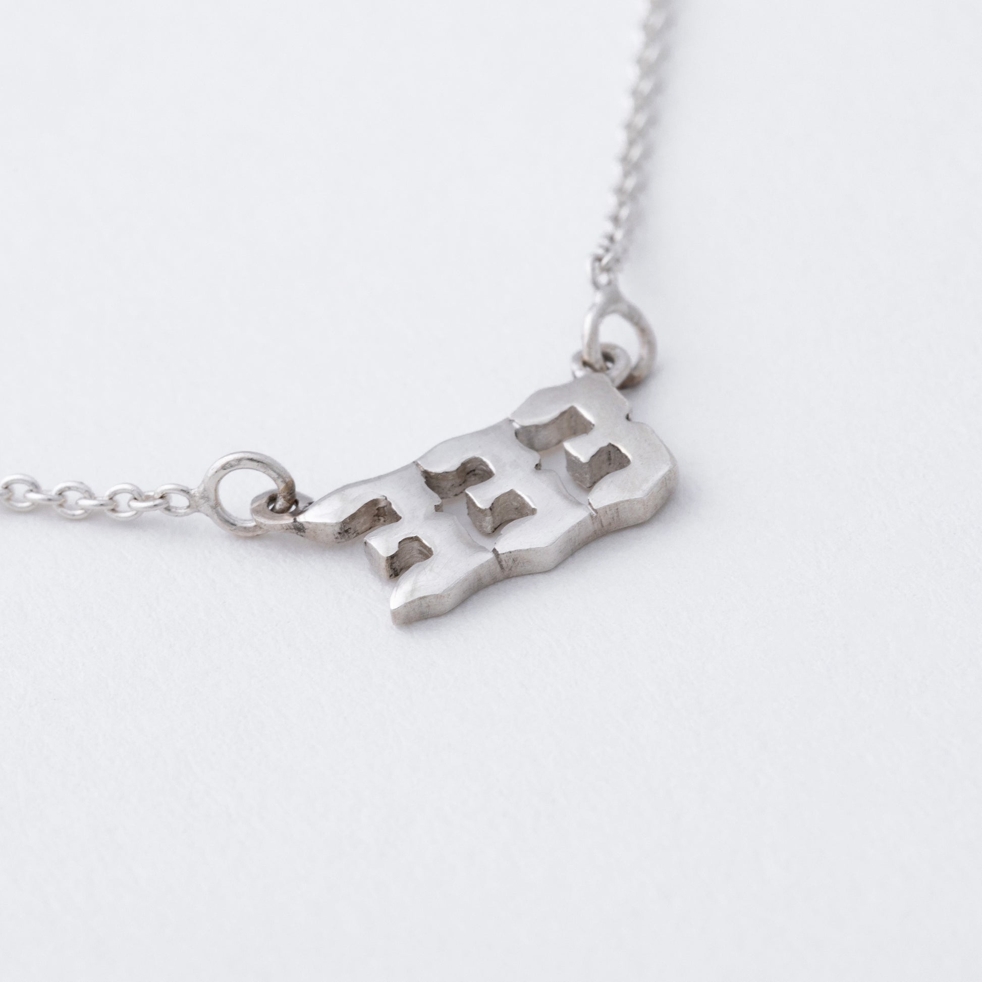 Silver necklace with a map pendant on a white background
