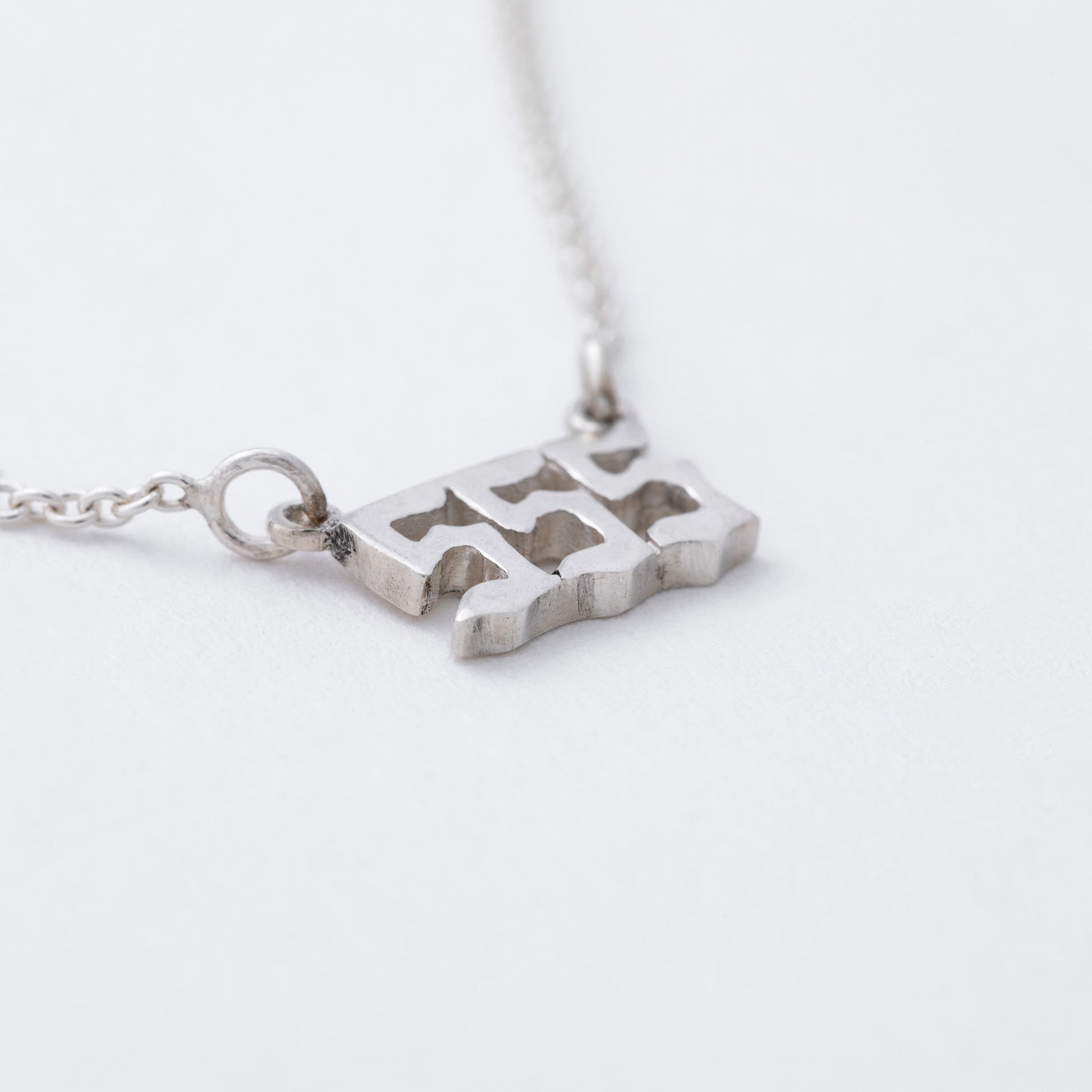 Silver necklace with a unique pendant on a light gray background