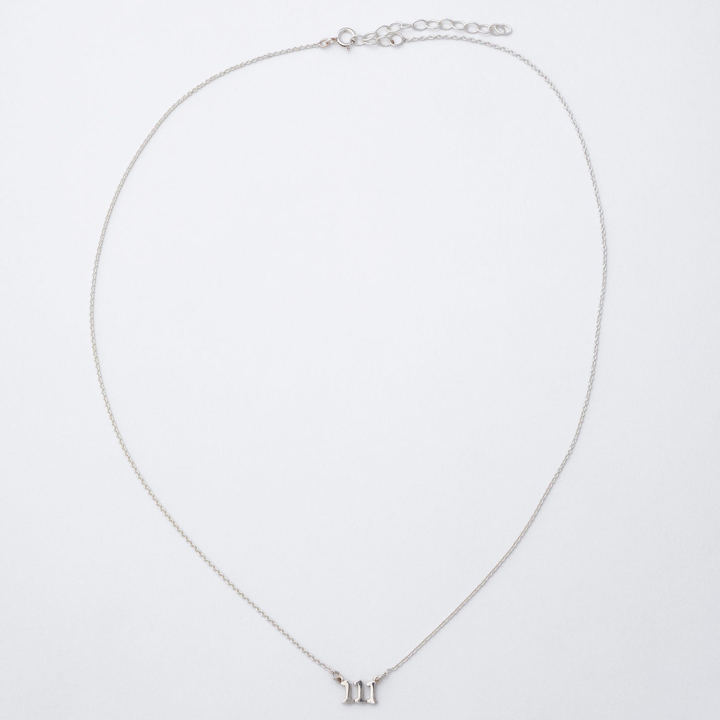Silver necklace with a small pendant on a light gray background