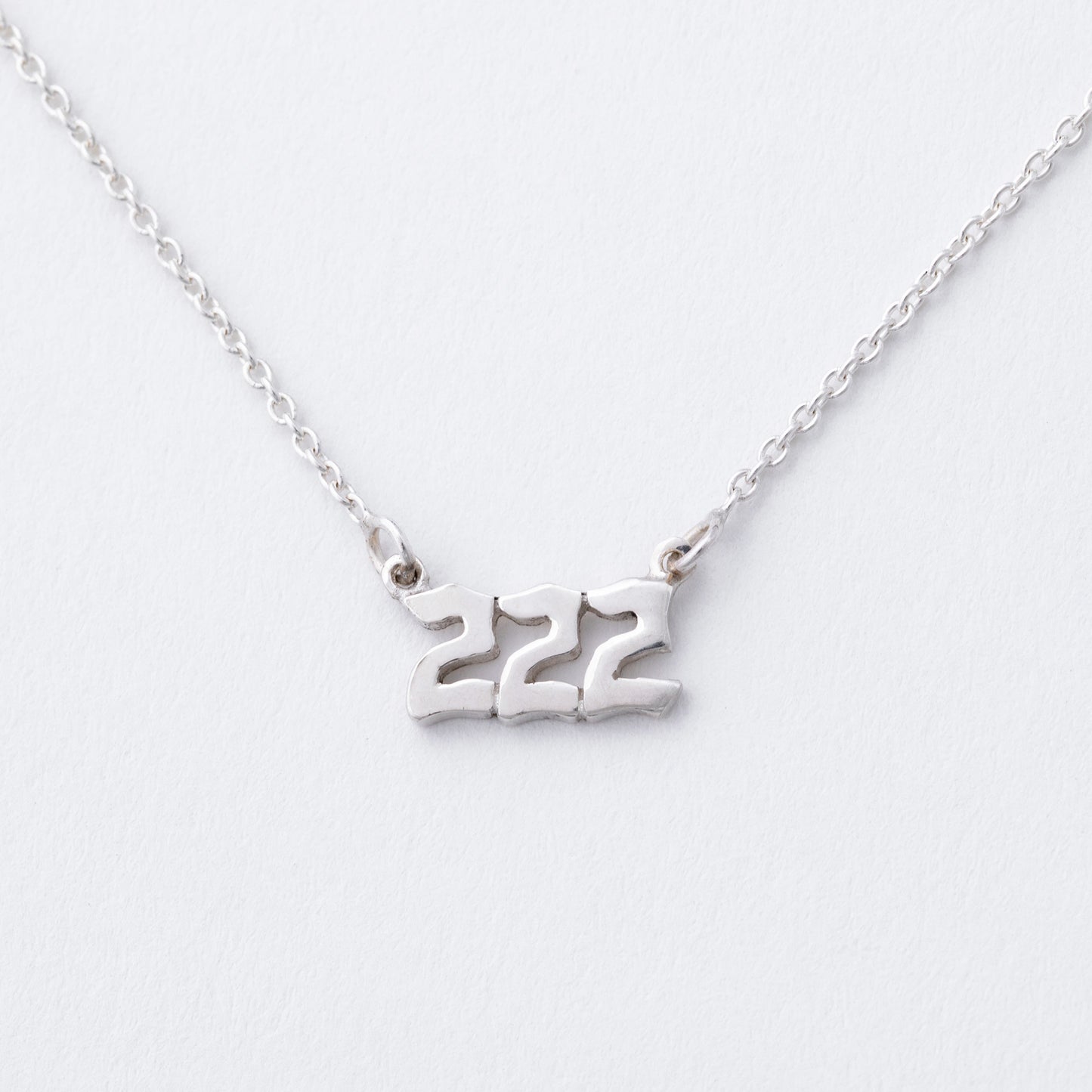 Silver necklace with the number '222' on a white background