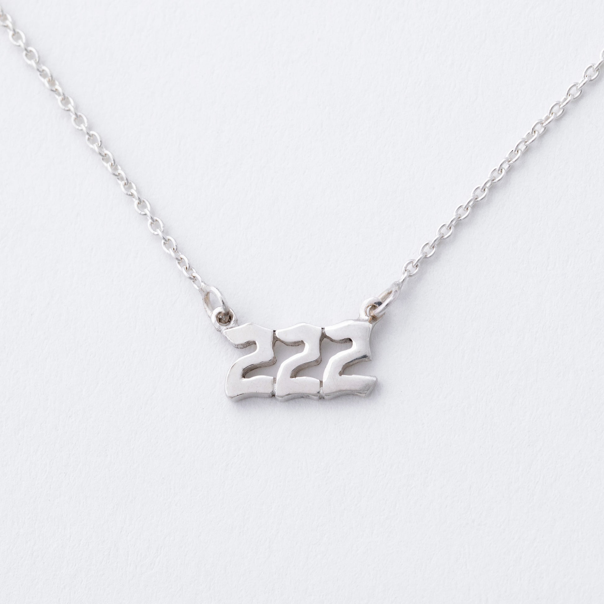 Silver necklace with the number '222' on a white background