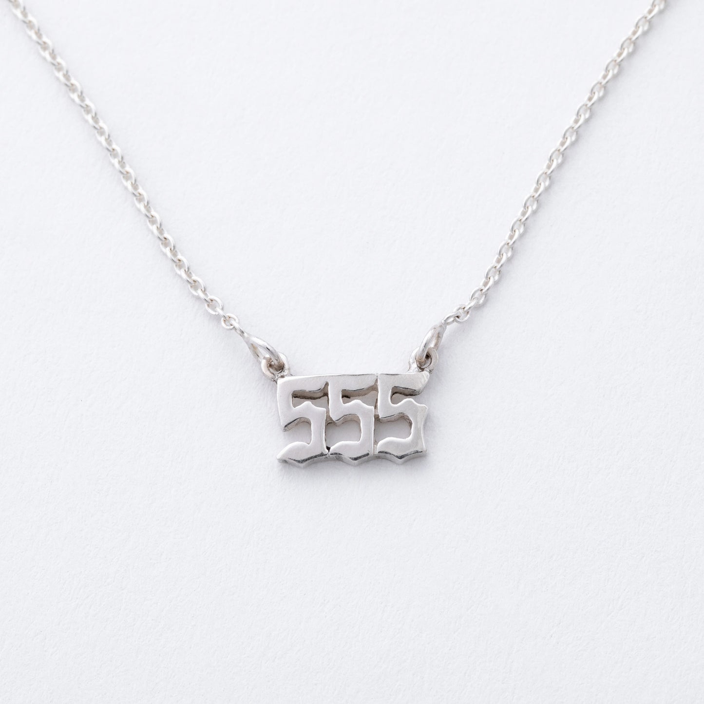 Silver necklace with '555' pendant on a white background