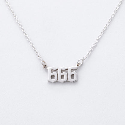 Silver necklace with '666' pendant on a white background