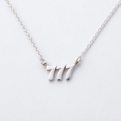 Silver necklace with the number '7' pendant on a light gray background