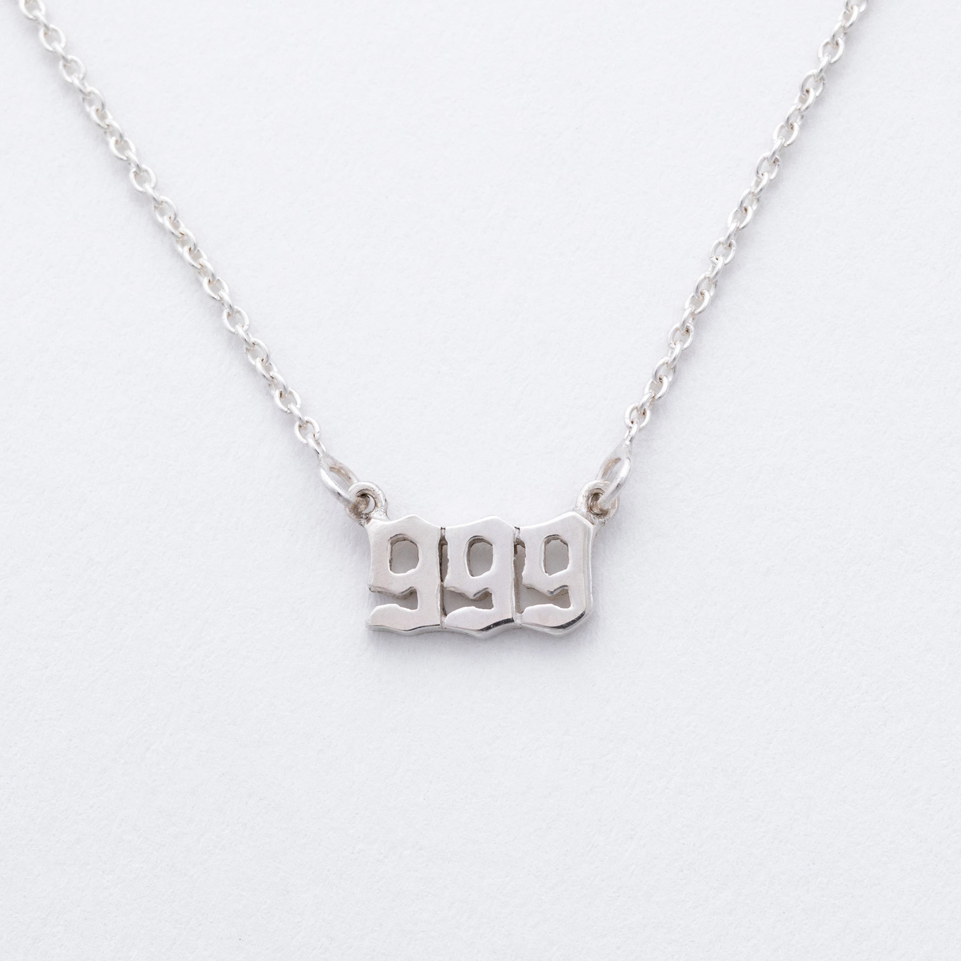 Silver necklace with '999' pendant on a white background