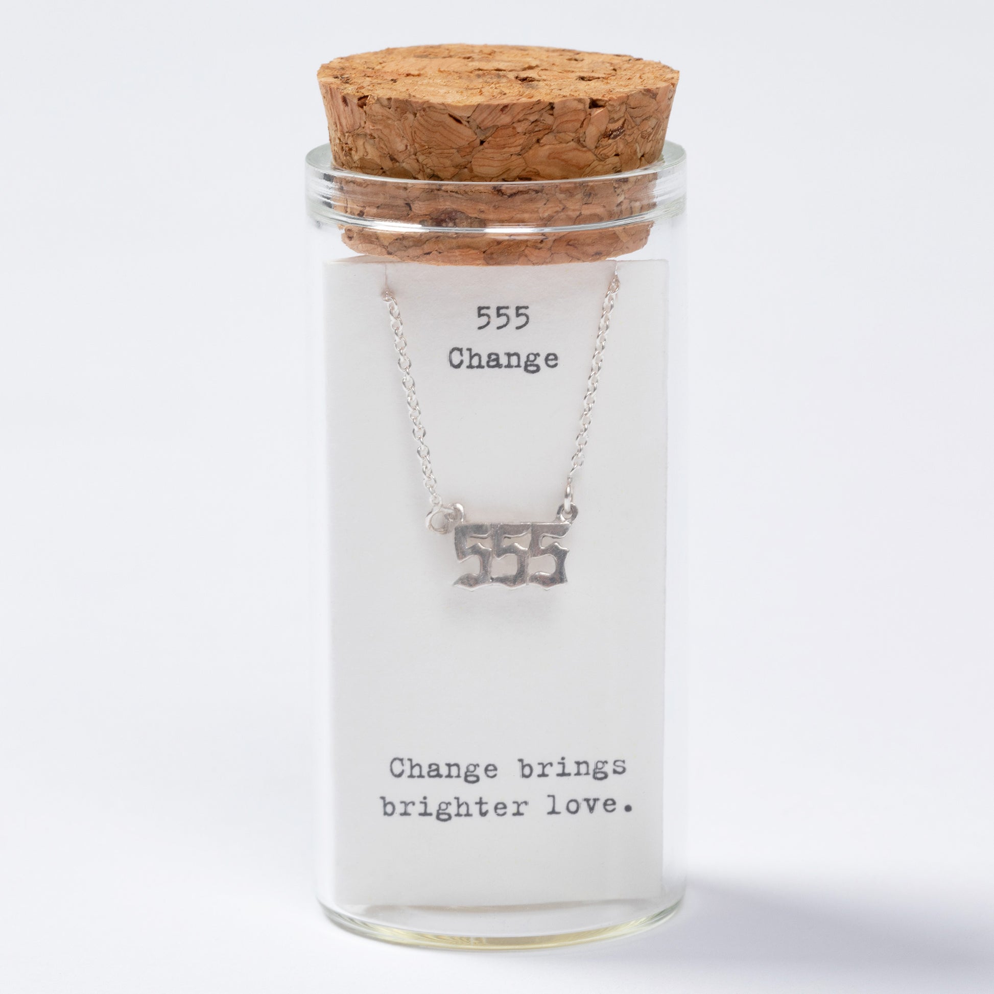 Glass jar with cork lid containing a necklace labeled '555 Change brings brighter love' on a white background
