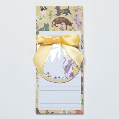Notepad with a decorative border featuring cats and flowers, tied with a yellow ribbon.